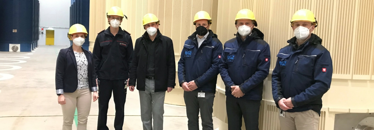 Lena Wieland (Leiterin Überwachung), Marc Weinert (Kommandant der Freiwilligen Feuerwehr Neckarwestheim), Bürgermeister Jochen Winkler, Stefan Haas (Leiter Sicherung und Instandhaltung), Wolfgang Arnold (Hauptabteilungsleiter Betriebe Südwest) und Thomas Taschke (Leiter des Zwischenlagers) vor leeren TN 24 E-Behältern im Brennelemente-Zwischenlager in Neckarwestheim.